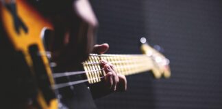 person playing sun burst electric bass guitar in bokeh 96380 scaled