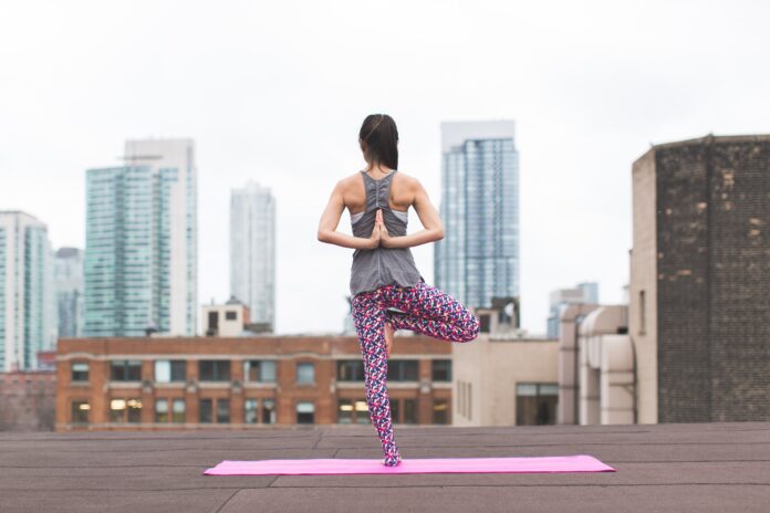 woman standing on pink yoga mat meditating 373946 scaled
